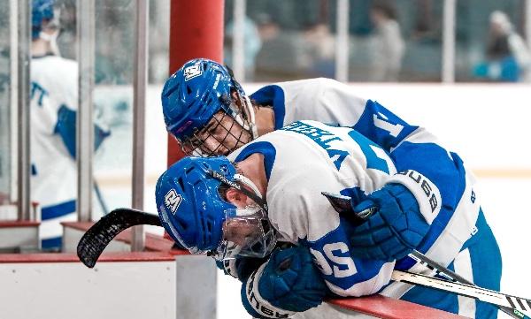 一名身穿蓝色制服的冰球运动员在输掉比赛后安慰他的队友. 