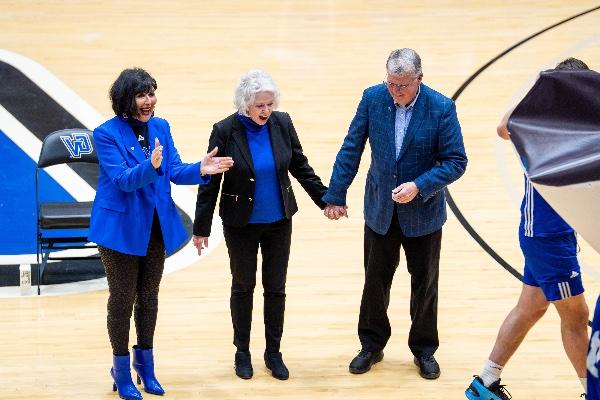  一位戴着蓝色拍子的大学校长，以一位前大学校长的名字命名的篮球场, pictured holding hands with his wife, is unveiled. 