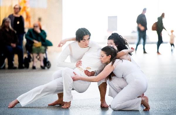 College dancers perform a modern dance routine wearing all white. 